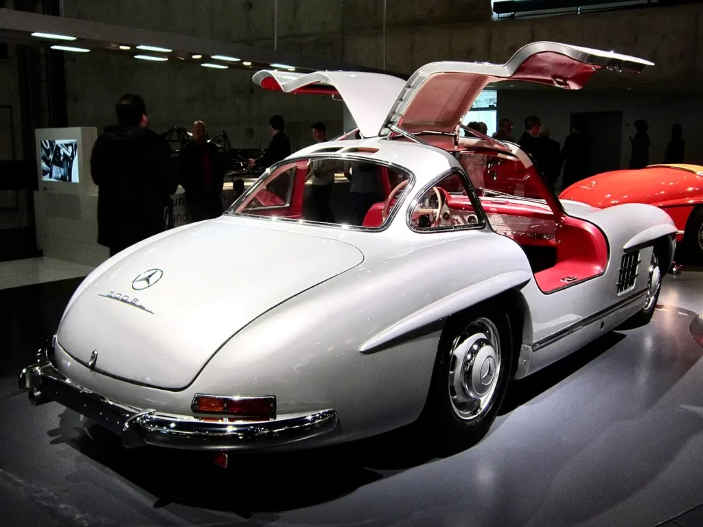 - MotorGuru.cz Mercedes Benz 300 SLR Uhlenhaut Coupé s otevřenými křídlovými dveřmi a červeným interiérem vystavený v muzeu značky ve Stuttgartu