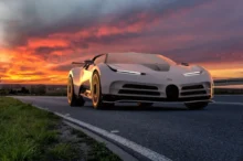 Bílé Bugatti Centodieci projíždí po silnici při západu slunce