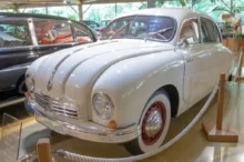 Bílý osobní automobil Tatra 600 vystavený v muzeu, obklopený dalšími historickými vozy
