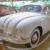 Bílý osobní automobil Tatra 600 vystavený v muzeu, obklopený dalšími historickými vozy