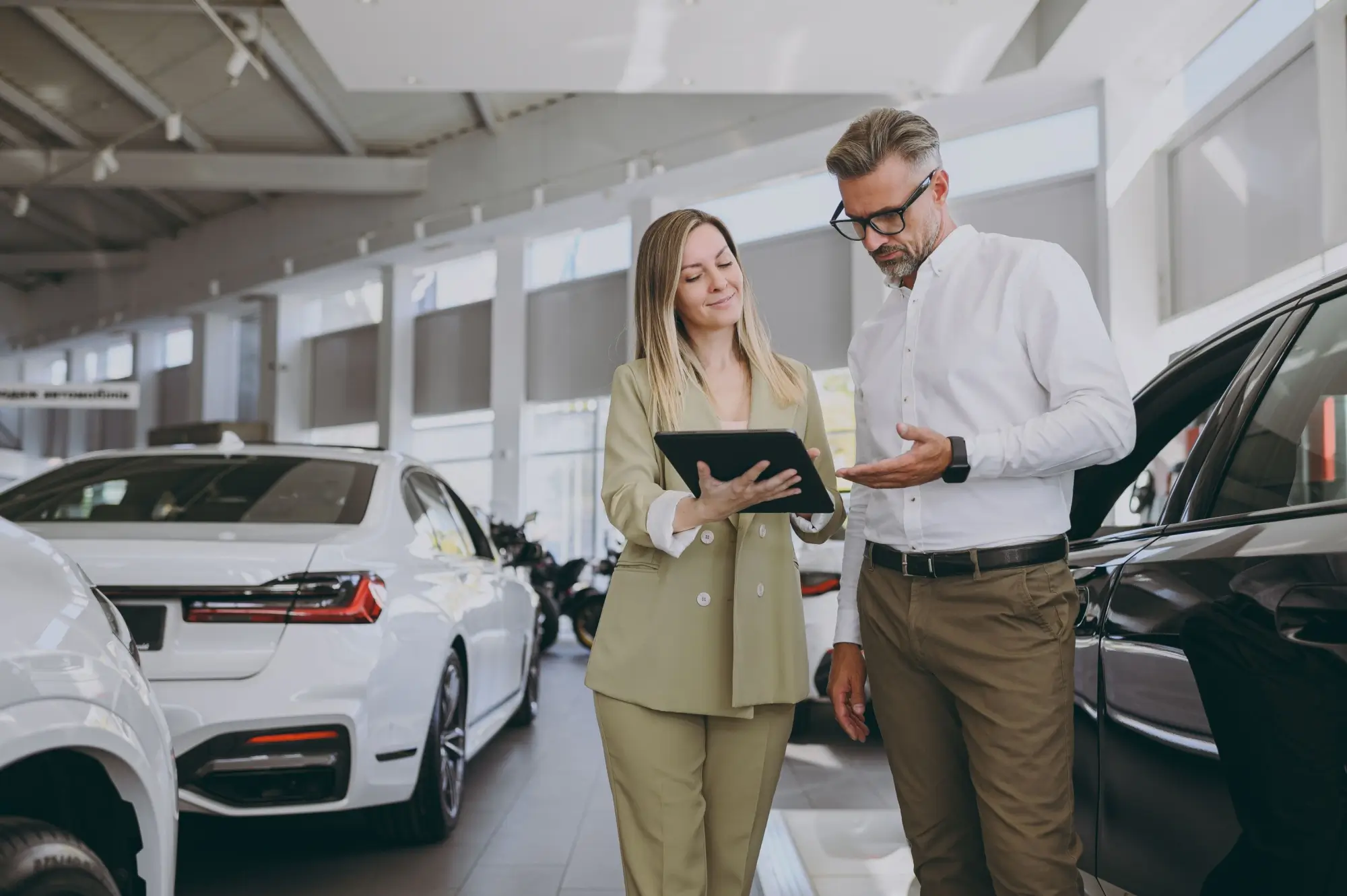 - MotorGuru.cz Mladá žena vysvěltující pojištění při koupi nového vozu.