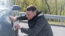 Muž kontroluje auto po bouračce