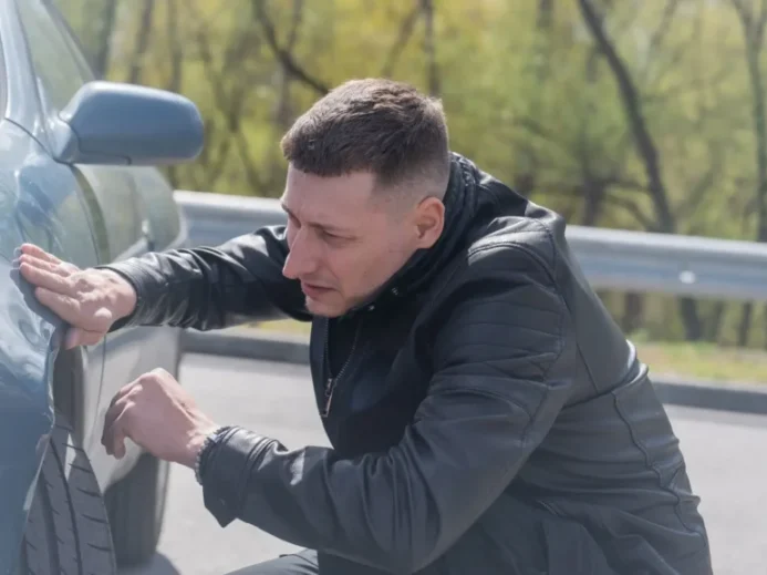 Muž kontroluje auto po bouračce