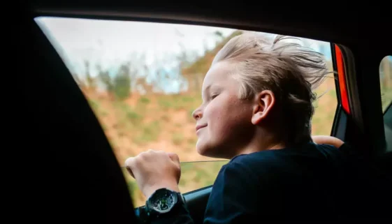 dítě vykukující z okna auta