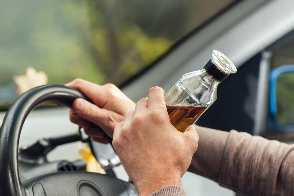 Muž za volantem s alkoholem
