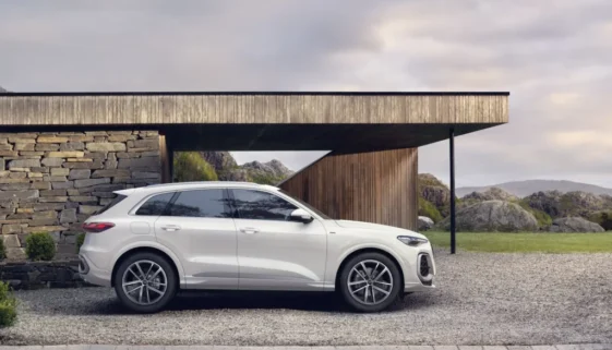 Bílá Audi Q5 zaparkovaná před moderním domem v horské krajině