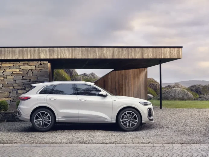 Bílá Audi Q5 zaparkovaná před moderním domem v horské krajině