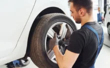 Automechanik nasazuje kolo na vůz v autoservisu