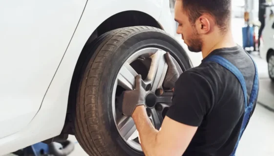 Automechanik nasazuje kolo na vůz v autoservisu