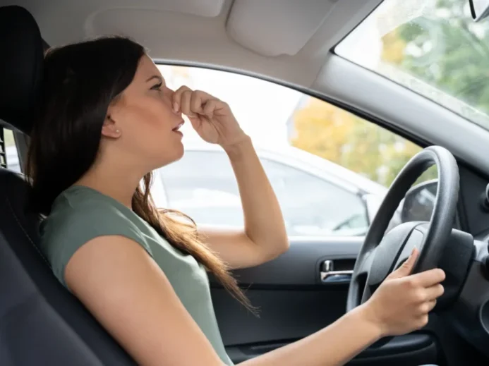 Žena se drží za nos v autě