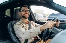 muž s brýlemi řídí auto