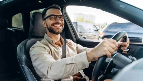 muž s brýlemi řídí auto