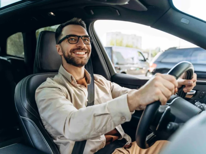 muž s brýlemi řídí auto