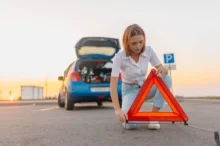 Žena staví za auto výstražný trojúhelník