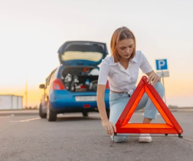 Žena staví za auto výstražný trojúhelník