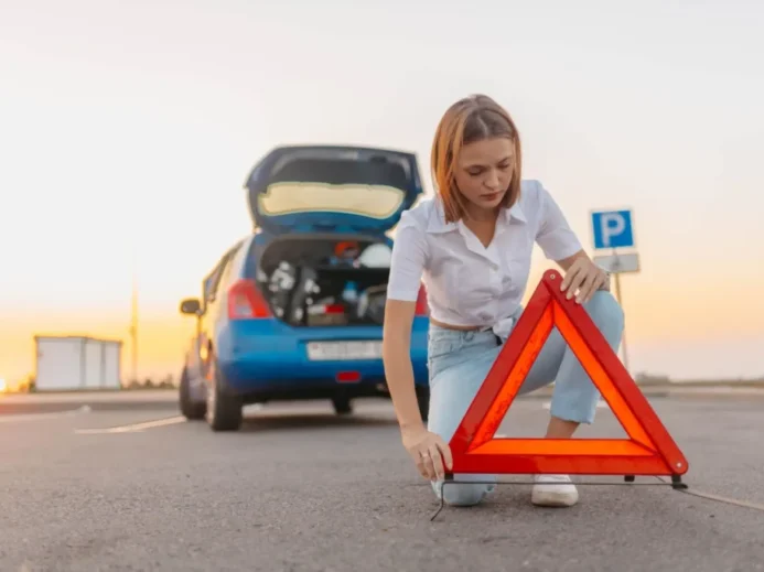 Žena staví za auto výstražný trojúhelník