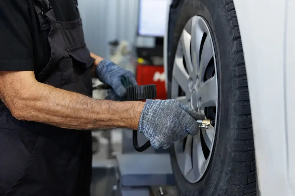 Automechanik měří tlak v pneumatikách